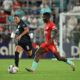 Two players dribble the ball on the soccer field