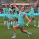 Kansas City Current midfielder Lo'eau LaBonta strikes a pose while celebrating a goal. She is lunging forward on one knee with both arms extended to her sides.