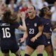 Two players celebrate on the field in blue jerseys after a goal is scored