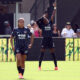 Gift Monday makes a shooting arrow motion in the background, celebrating a goal.